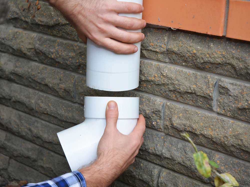 man-attaches-gutter-on-roof-porch