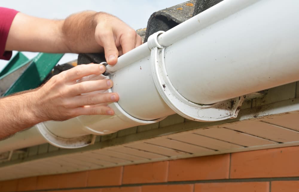 man-installing-repairing-roof-gutter-fitting