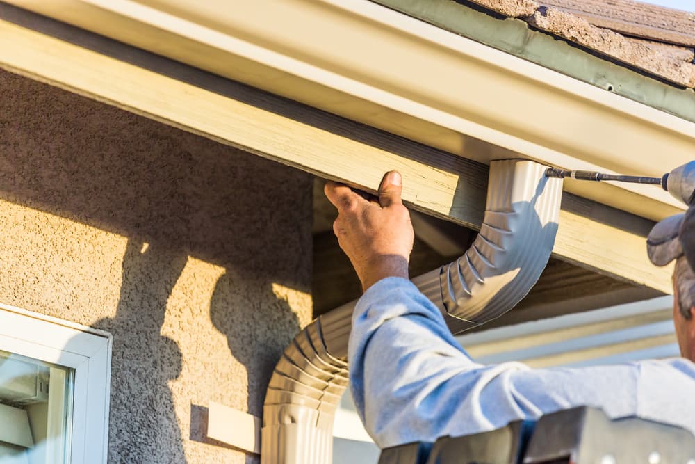 worker-attaching-aluminum-rain-gutter-down