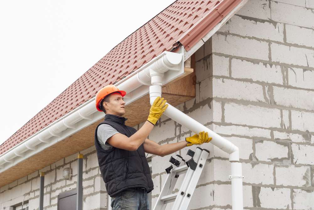 construction-worker-installs-gutter-system-on