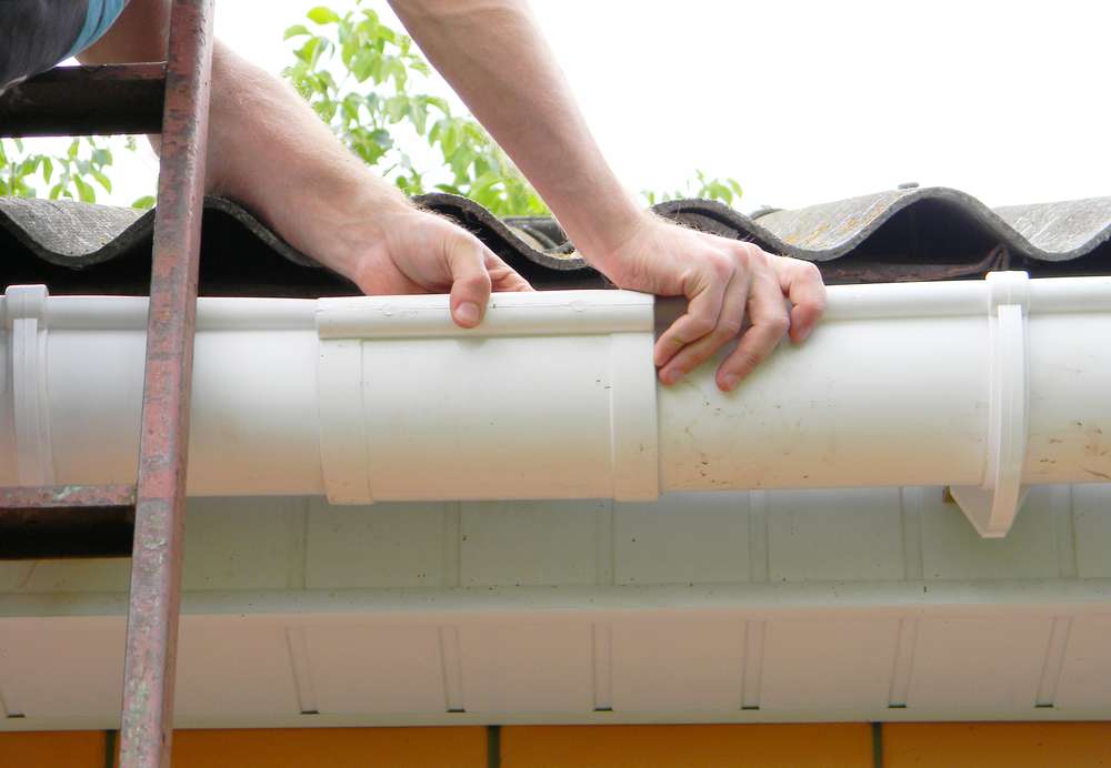 contractor-installing-plastic-roof-gutter-pipeline