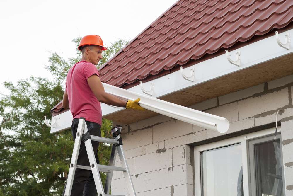 worker-installs-gutter-on-roof