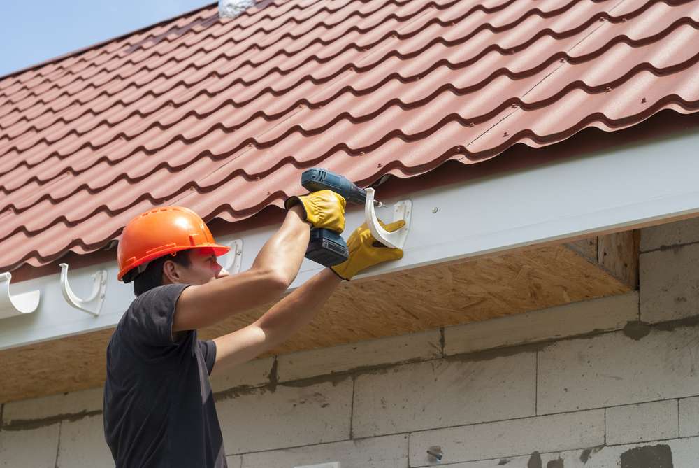 worker-installs-gutter-system-on-roof